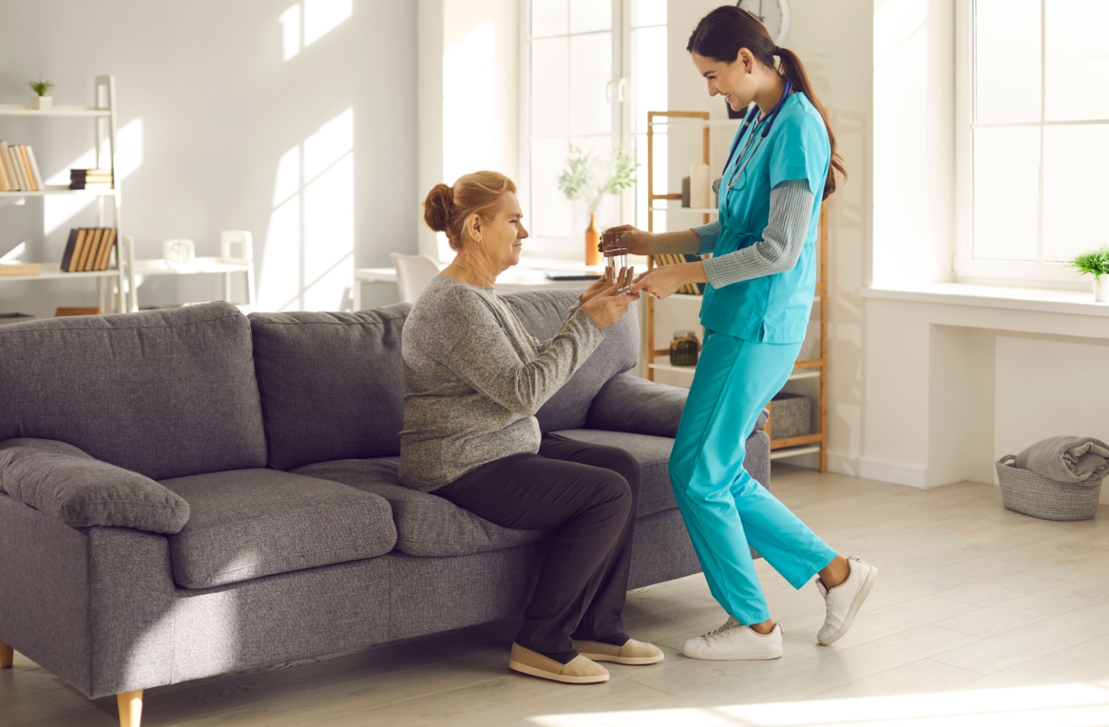 An assisted living caregiver helps a senior resident with their medication.