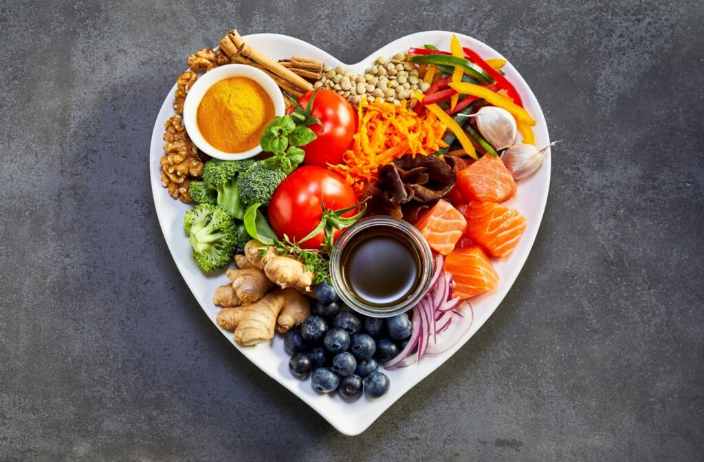 A heart-shaped plate covered in heart-friendly assorted foods like berries, fish, nuts, and more.